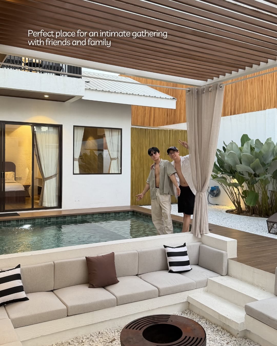 Full villa view — two guests by the pool with sunken lounge and retractable pergola